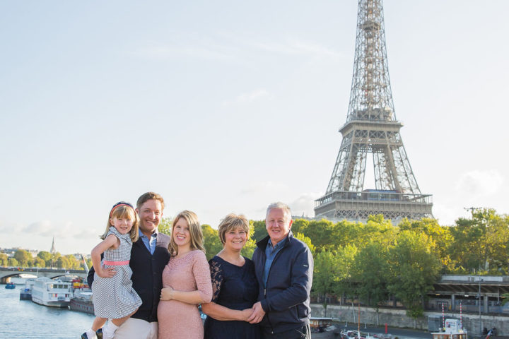 Family photo in Paris taken in front of the Eiffel Tower along the Seine.
